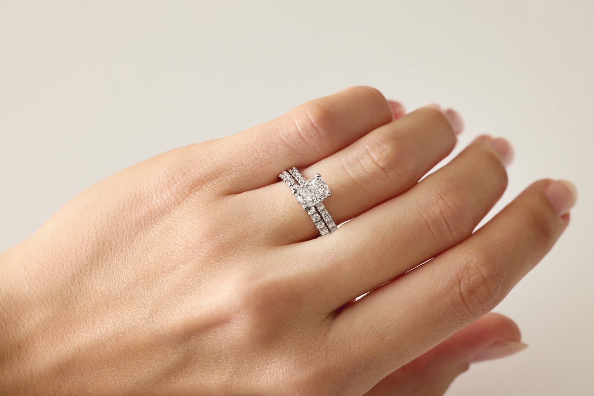 Cushion-cut diamond engagement ring and matching band worn on a hand